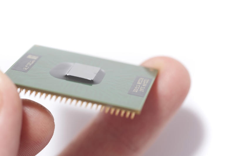 Microsoft ending 32-bit support: Close-up image of man holding CPU chip in fingers against white background