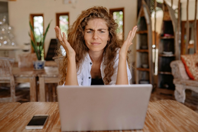 a young woman staring at her laptop frustrated: Windows Keeps Waking Up from Sleep